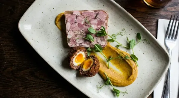 Ham hock terrine, pea shoots, warm Scotch egg and curried beans