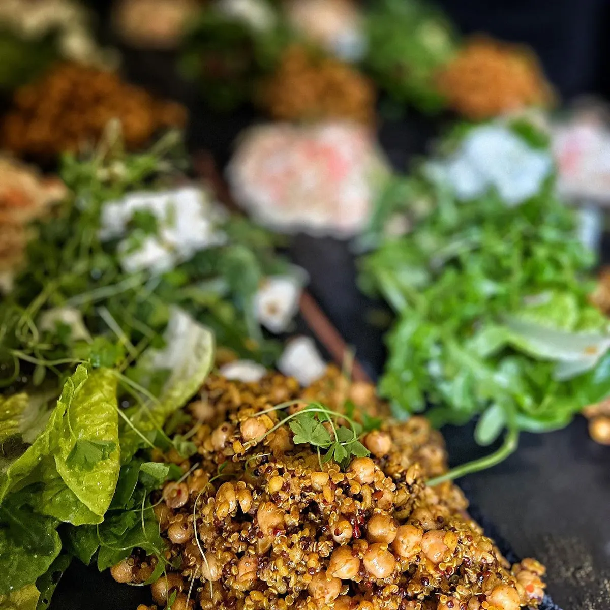 Spiced chickpea and quinoa salad with fresh leaves and pea shoots on a buffet table